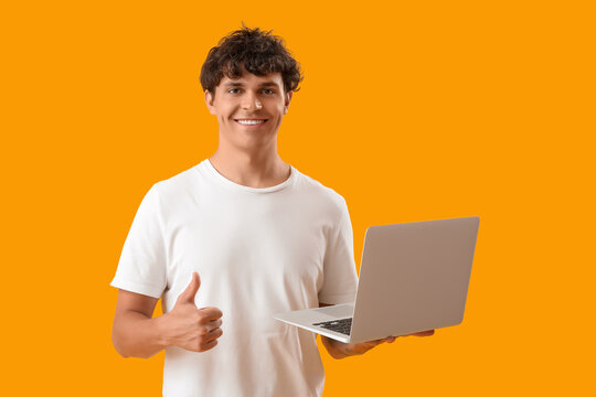 Male programmer with laptop showing thumb-up on yellow background