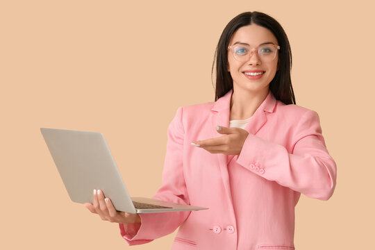 Female programmer with laptop on beige background