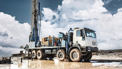 The drilling rig stands at the worksite extracting oil and gas resources. Clouds cover the sky as...