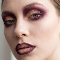 close up woman face with dramatic purple makeup and lipstick