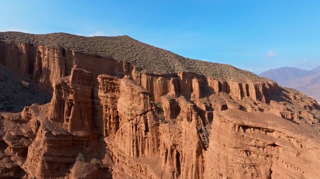 Dramatic rock formations rise majestically in an arid desert Konorchek Canyon in Kyrgyzstan. Descending drone view.