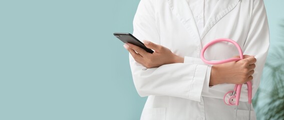 Female doctor with stethoscope and mobile phone in clinic, closeup