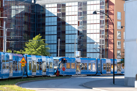 Modern metro train approaches a transit station near city buildings capturing urban transportation in Stockholm Sweden with vivid blue carriage