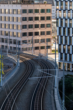 Modern urban infrastructure features railway tracks on a curving viaduct next to city architecture in Stockholm Sweden under clear daylight