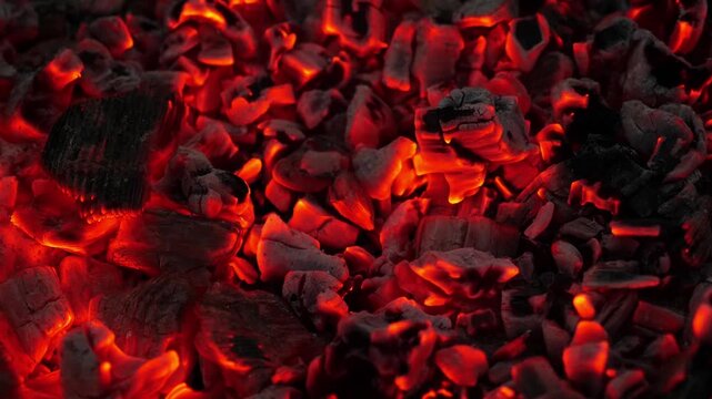 Detailed close-up of embers slowly cooling, with sparks and ash in motion.