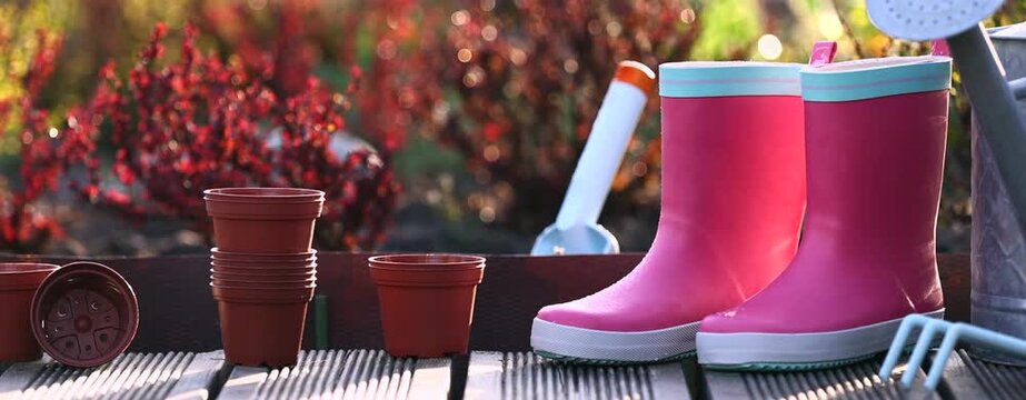 Pink boots and gardening tools on a wooden terrace