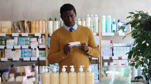 Male buyer in glasses buys medicinal ointment at a pharmacy. High quality 4k footage