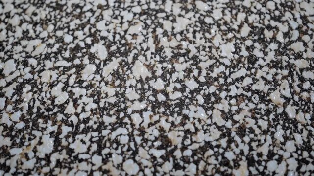 Close-up, top-down view of a textured terrazzo surface, showcasing a mix of white and brown chips. Ideal for a video background or design inspiration.
