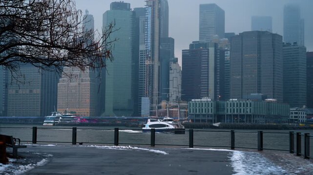Majestic high-rise buildings of New York in the fog. Motor boat moves by the waterscape of the river on misty day.