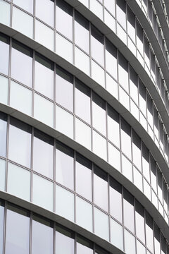 Glass facade with modern curves and pattern on corporate office building architecture and windows creates a refined business design closeup