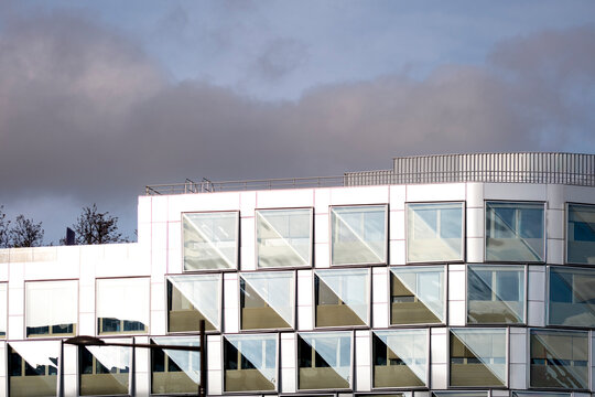 Geometric pattern on modern facade windows of corporate office building shows architecture set against open sky with strong graphic rhythm