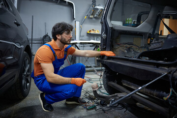 Auto technician inspecting dismantled car in garage workshop