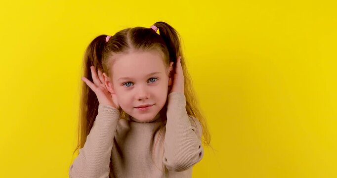 Caucasian girl leaning and cupping her ear as if eavesdropping on a bright yellow background. Concept of curiosity, secret, listening, and playful behavior. Isolated, high contrast, 4K video.