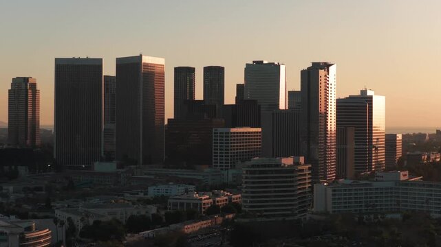 Telephoto aerial dolly shot of Century City from Beverly Hills at sunset in Los Angeles, California. 4K