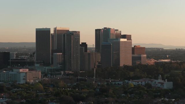 Telephoto panning aerial shot of Century City at golden hour in Los Angeles, California. 4K