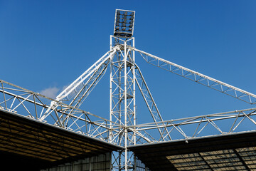 Fototapeta premium Metal stadium lighting tower with lamps and blue sky background
