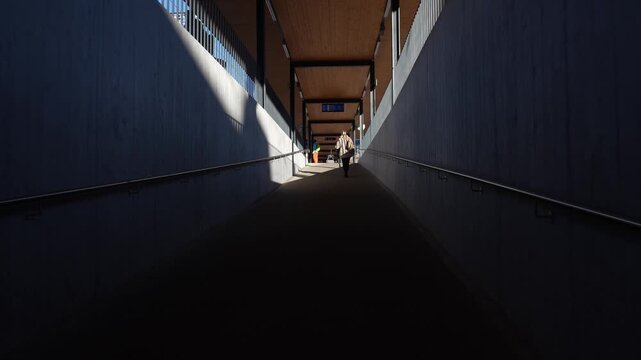 Woman walking alone through a modern underpass ramp tot ake the train in switzerland