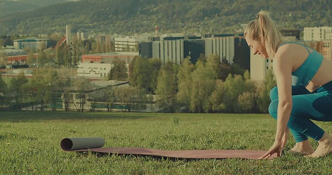 Woman Unrolling Yoga Mat in Park on Sunny Spring Day