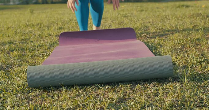 Woman Unrolling Yoga Mat in Park on Sunny Spring Day