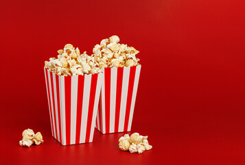 Two striped popcorn buckets on red background with copy space. Cinema date concept.