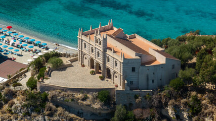 Aerial closeup of the Sanctuary of Santa Maria dell'Isola in Tropea, Calabria, Italy. The ancient church stands on a rocky promontory, overlooking the Mediterranean sea. It is a sunny summer morning. © Stefano Tammaro