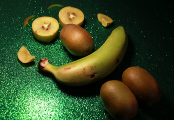 Kiwi y pl&aacute;tano con cara creativa, original y simp&aacute;tica con piezas de fruta sobre fondo verde brillo
