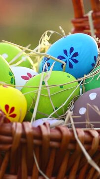 Easter eggs on green spring grass with basket in sunlight. Vertical