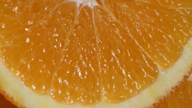 Extreme close-up of ripe orange slices spinning in slow motion. Detailed view of citrus texture, glowing pulp, and fresh juice. Water droplets on the peel enhance the freshness concept. Perfect for hy