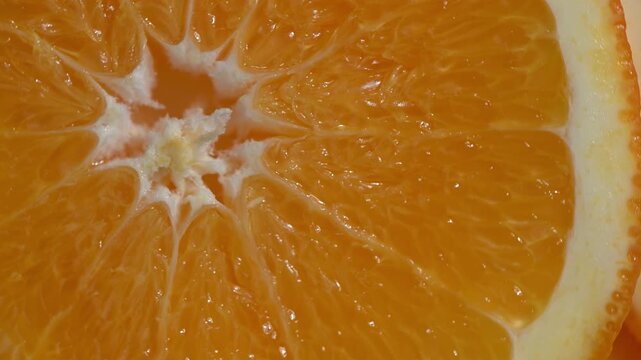 Freshly sliced juicy oranges arranged in a circle and rotating slowly on a turntable. Close-up shot of vibrant citrus fruit wheels with visible pulp and texture. Perfect for healthy food, vitamin C, o