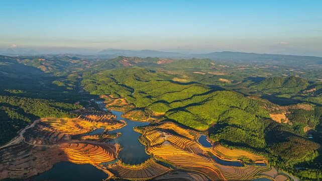 Drone landscape of Tad Ma Waterfall revealing expansive rice fields and green valleys, highlighting a rich agricultural area supported by nearby dams in Vientiane.