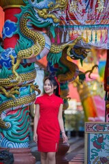 Fototapeta premium Young Woman in Traditional Red Dress Near Colorful Dragon Decorations