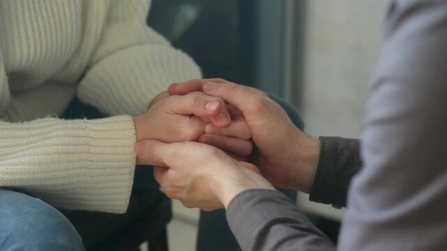 Close up caring man gently holding stroking hands worried woman, offering support, empathy, comfort during difficult conversation therapy session. Supportive man comforting anxious woman holding hands