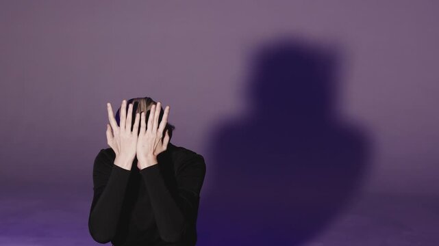 A young woman uncovers her face with her hands and looks around with a worried, disoriented expression. Close-up video capturing deep human emotion and psychological tension.