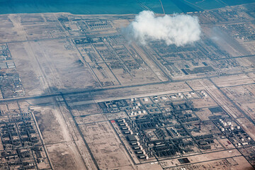 Industrial complex with storage tanks and processing units along a desert coastline