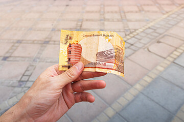 Hand holding a Bahrain half dinar banknote, representing economy and finance