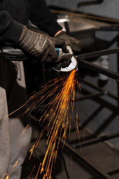 Worker grinding steel with angle grinder sparks in industrial workplace