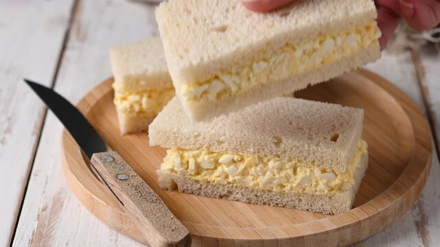 Catching Tamago Sando sandwich on wooden table. Traditional japanese sandwich