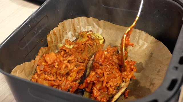 A person is putting food in a pan that is in an oven. The food is covered in sauce and he is meat