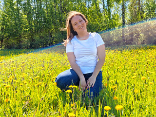 Young woman enjoying a sunny day in a field of yellow flowers surrounded by greenery