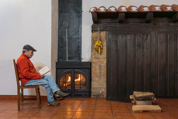 Man relaxing reading book by a warm fireplace