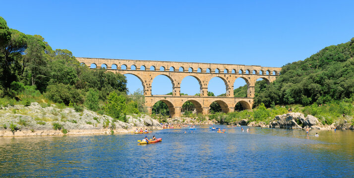 Roman Aqueduct Pont du Gard over River Gardon - important Bridge structure of antiquity and UNESCO World Heritage with people in Mediterranean landscape Occitanie - Vers-Pont-du-Gard France 2025-06-28