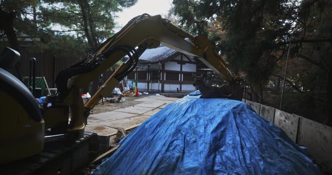 Deer laying on construction tarp near excavator - steady cam movement 