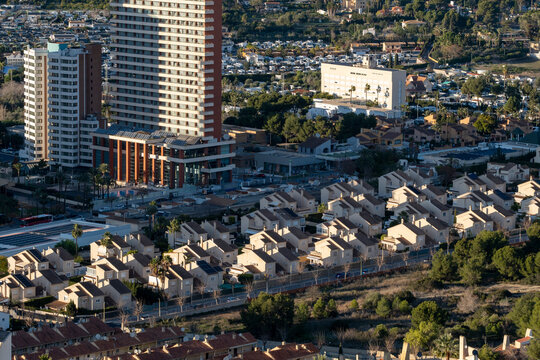 Daylight on apartments and highrise buildings defines an urban neighborhood housing scene on a hillside in Benidorm Spain with dense rooftops