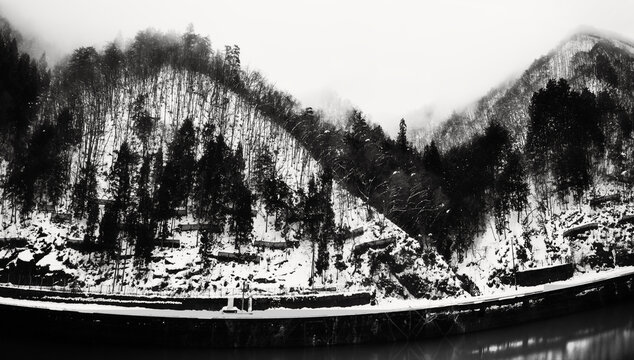 Serene snow‑covered winter scenes of the Hida Mountain foothills of the Japanese Alps along the Miyagawa River in Gifu Prefecture, Japan in a black‑and‑white retro style.