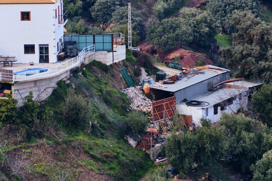 Aerial view of a building on a steep slope, with landslide, rocks are being in place held by scaffolding, Algatocin, Andalusia, Spain.
