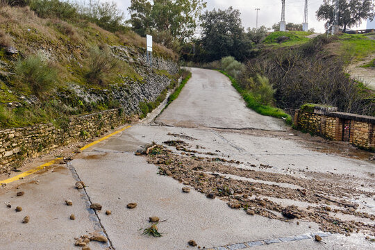 View of the road partially covered with mud and rocks after a landslide, surrounded by greenery, Setenil de las Bodegas, Andalusia, Spain.