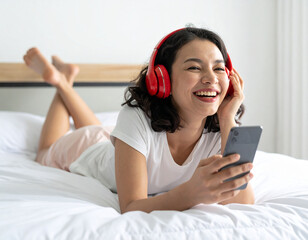 Lachendes junges Mädchen liegt auf dem Bett und hört Musik