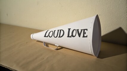 White Megaphone with Bold Text Saying Loud Love on Table Surface