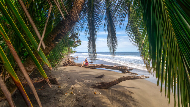 Girl with long hair posing in purple mini skirt on the caribbean beach Playa Puerto Vargas with palm trees in Cahuita National Park in Costa Rica