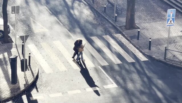 Mujer joven asistente social acompa&ntilde;ando en paseo a se&ntilde;ora anciana mayor de tercera edad cruzando la calle por paso de peatones
